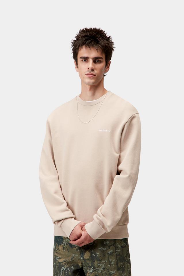Man wearing a beige sweatshirt and camouflage pants on a white background