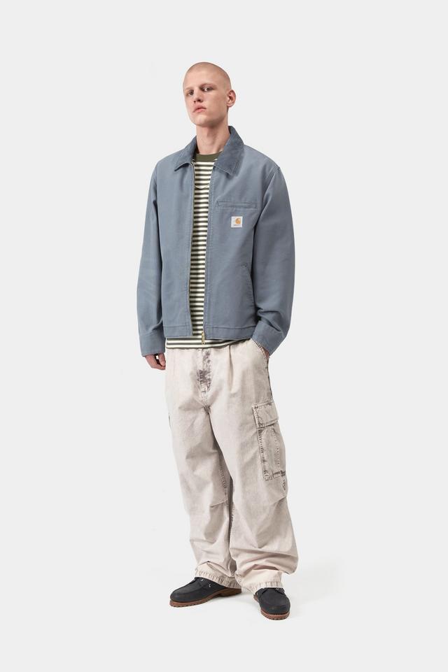 Person wearing a blue jacket, striped shirt, and beige pants on a white background