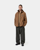 Carhartt WIP Blevin Liner in WIP H Brown, worn on a model with hood up, front view, with reflective Square Label and black trim visible.