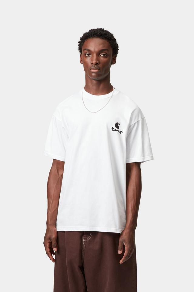 Person wearing a white t-shirt with a small black design on a plain background