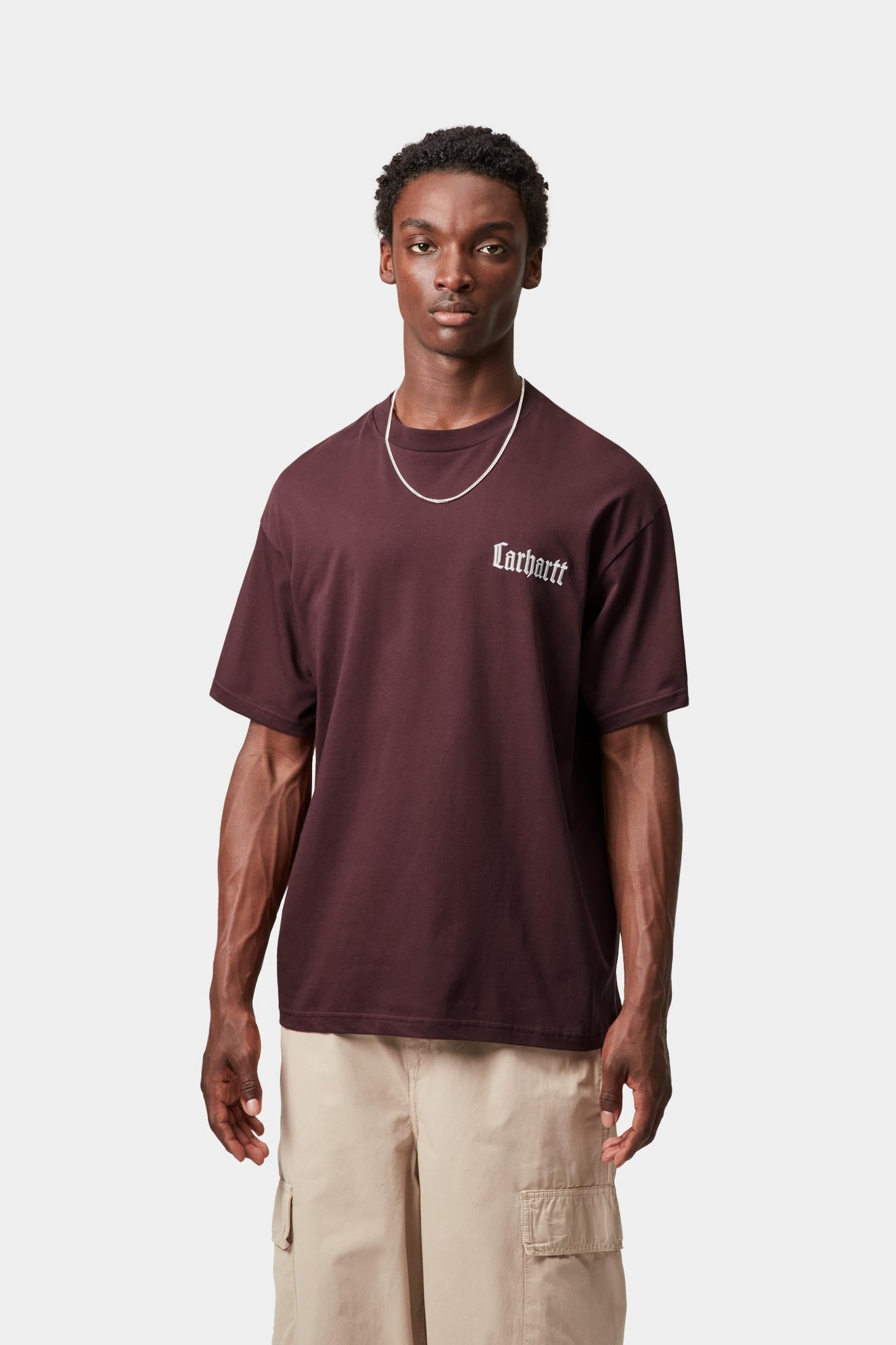 Man wearing a maroon t-shirt with a brand logo on a white background