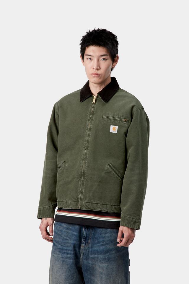 Person wearing a green jacket with a brand logo on a white background