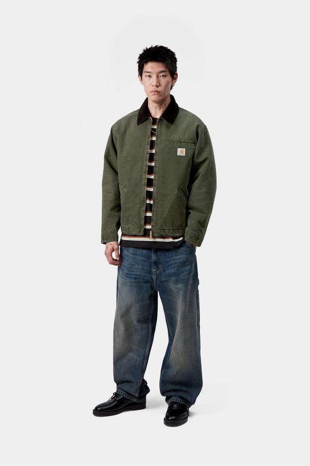Person wearing a green jacket with a brand logo on a white background