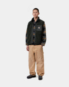 Carhartt WIP Prentis Vest Liner in Raven / Black, worn over a plaid shirt, with a chest pocket and funnel neck shown on model.