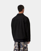 Back view of the Carhartt WIP Atoka Shirt Jac in Black, worn by a model. The unlined wool-blend jacket features a pointed collar, a back yoke with a centre box pleat, and a buttoned cuff on the sleeve.