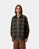Carhartt WIP Alton Jacket in Alton Check, Cypress worn by a male model, front view. The jacket features an allover check pattern, a pointed collar, a zip front closure, and two side welt pockets.