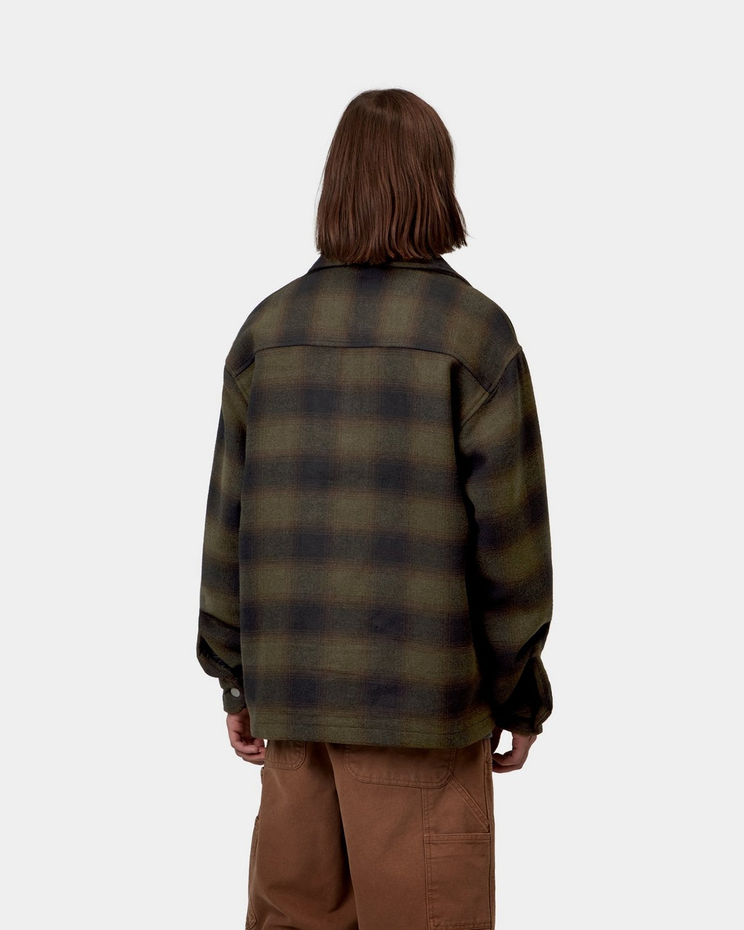 Back view of the Carhartt WIP Alton Jacket in Alton Check, Cypress, worn by a model. The heavyweight poly-blend twill outer features an allover check pattern, a back yoke seam, and buttoned cuffs.