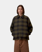 Front view of a model wearing the Carhartt WIP Alton Jacket in Alton Check, Cypress, a zip-front style with a pointed collar, two side welt pockets, and an allover check pattern.