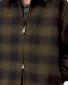 Close-up front view of the Carhartt WIP Alton Jacket in Alton Check, Cypress, showing the zip front closure with silver zipper pulls, the allover check twill fabric, and a collared shirt worn underneath.