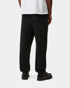 Carhartt WIP Chase Sweat Pant in Black / Gold, rear view, worn with a back pocket visible.