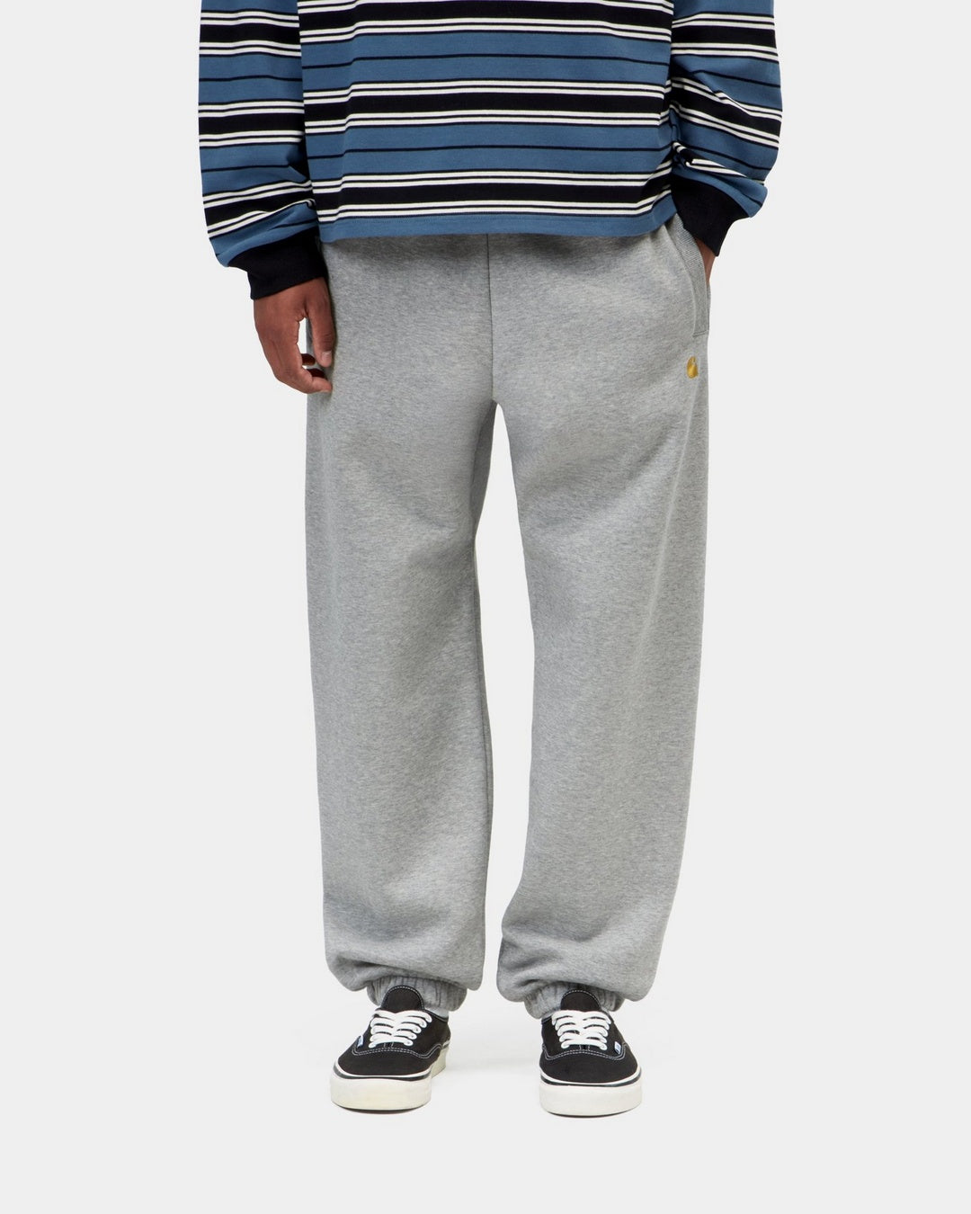 Carhartt WIP Chase Sweat Pant in Grey Heather with gold embroidered C logo, front view, worn with elasticated cuffs visible