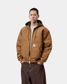 Carhartt WIP OG Active Jacket in WIP H Brown, front view, worn by model with hood up and zip closure, featuring kangaroo pocket and Square Label.