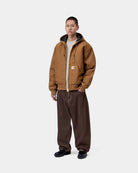 Carhartt WIP OG Active Jacket in WIP H Brown, front view on a model with hood up and kangaroo pocket visible.
