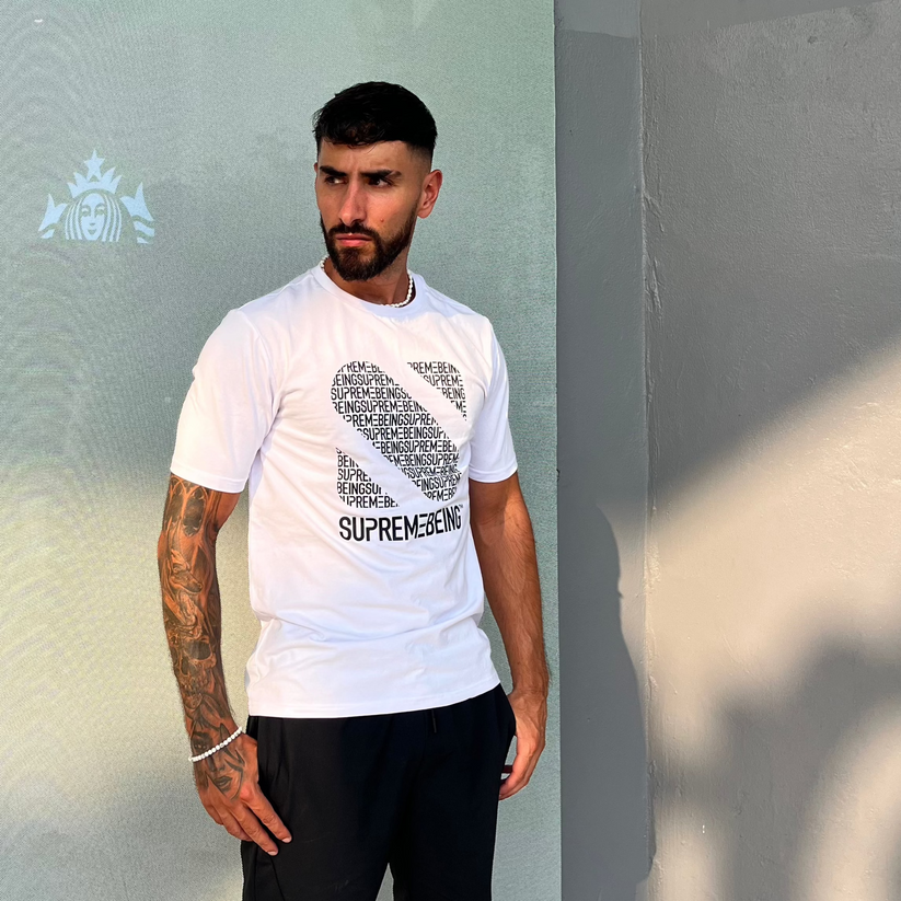 Man wearing a white t-shirt with black text standing against a light gray wall.