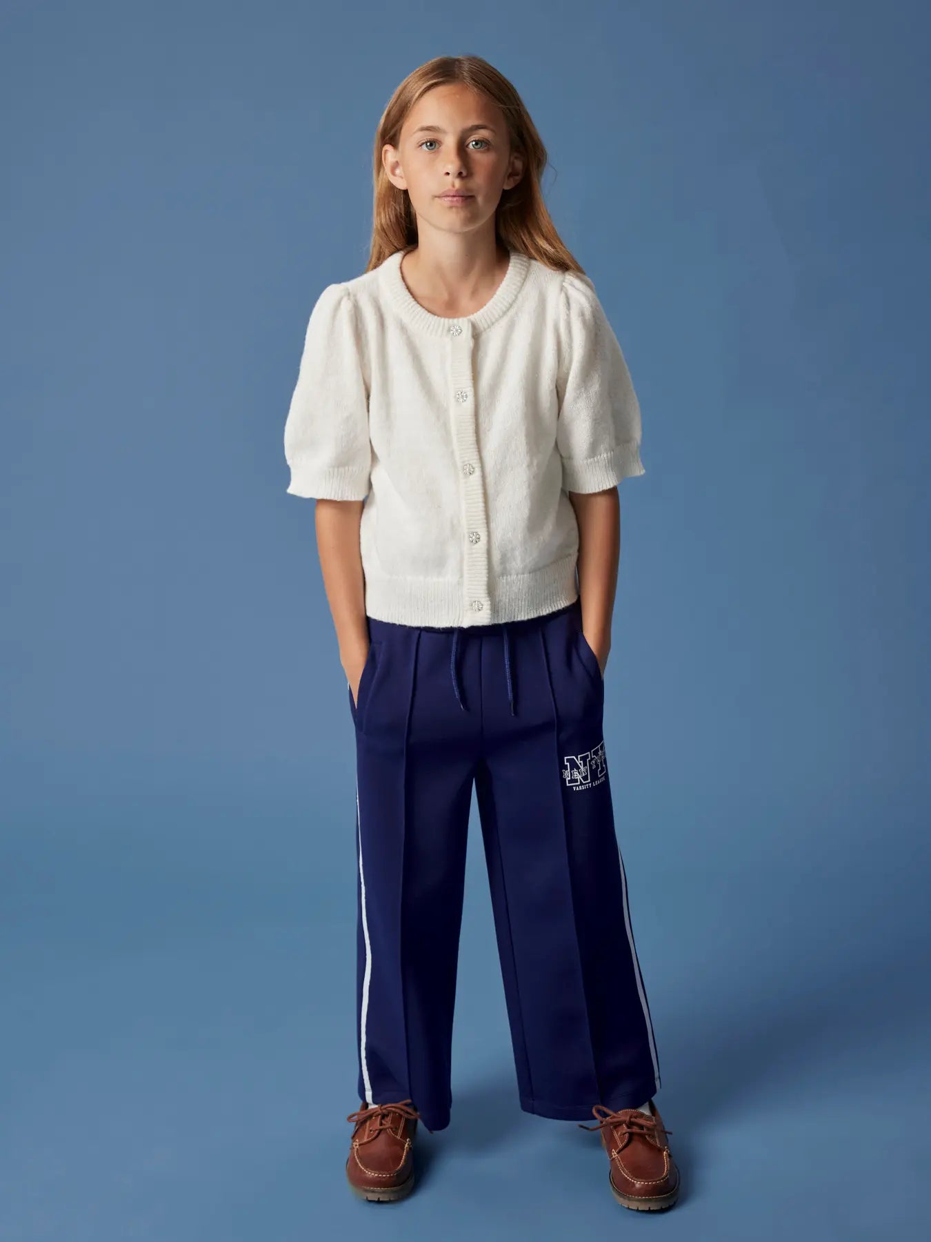 Person wearing a white shirt and blue pants with a logo on a blue background