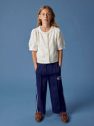 Person wearing a white shirt and blue pants with a logo on a blue background