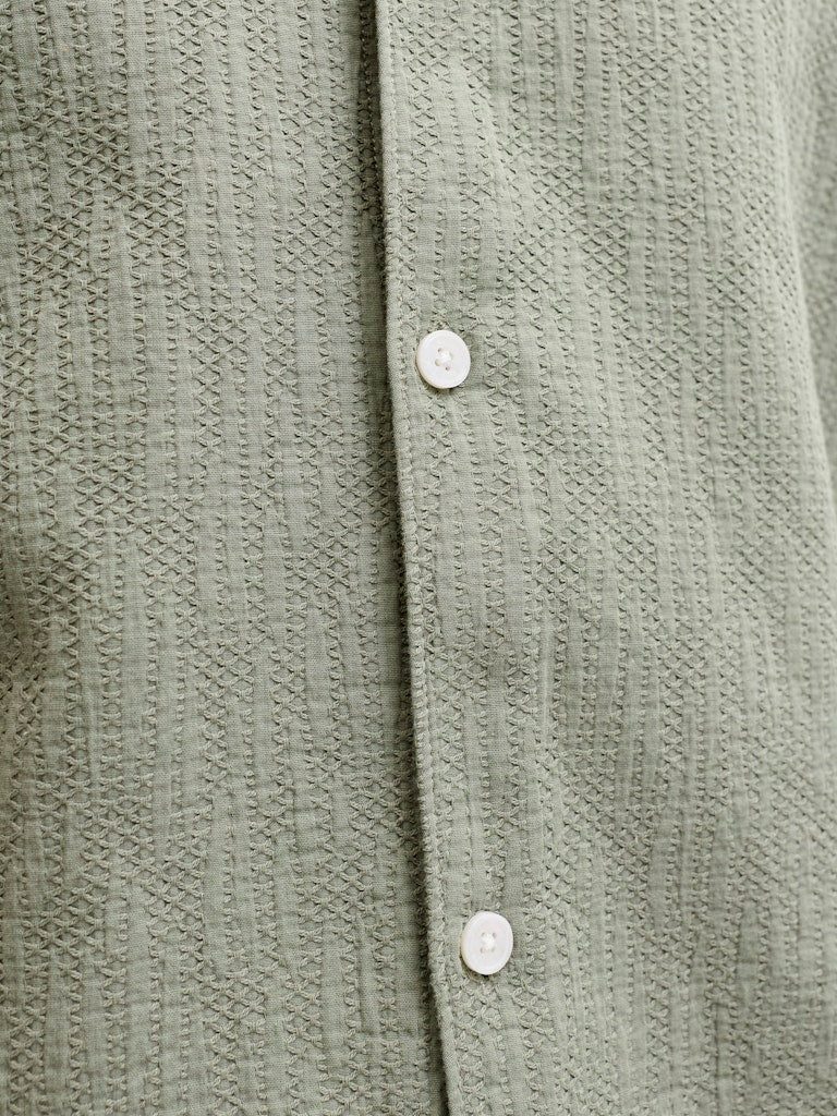 Close-up of a textured green shirt with buttons