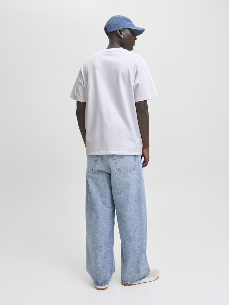 Person wearing a white t-shirt and light blue jeans on a plain background