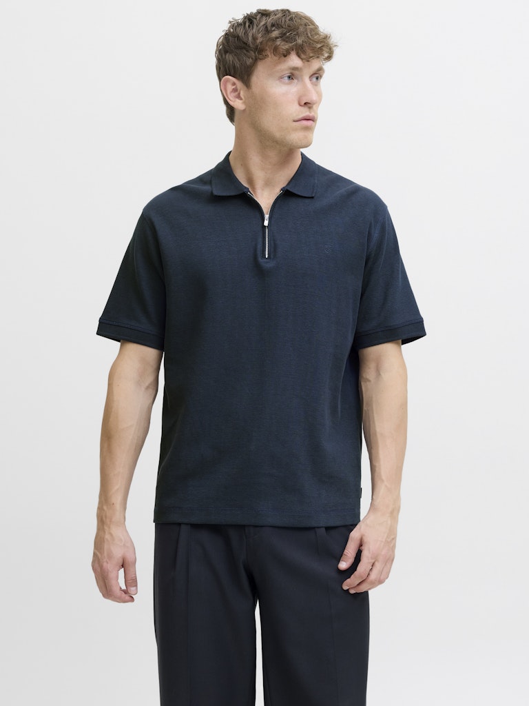 Man wearing a navy polo shirt and pants on a light gray background