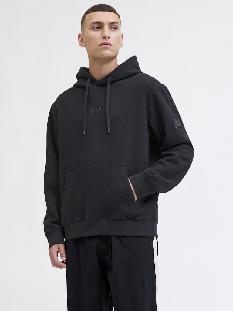 Person wearing a black hoodie with a brand logo on a light gray background