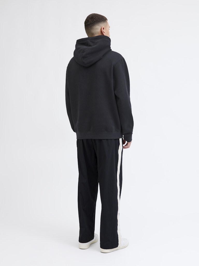 Person wearing a black tracksuit with white stripes on a white background