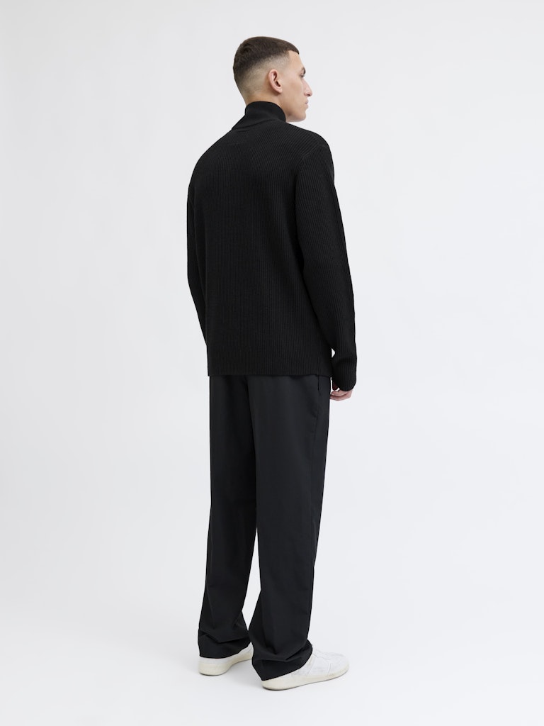 Man wearing a black outfit on a white background from behind