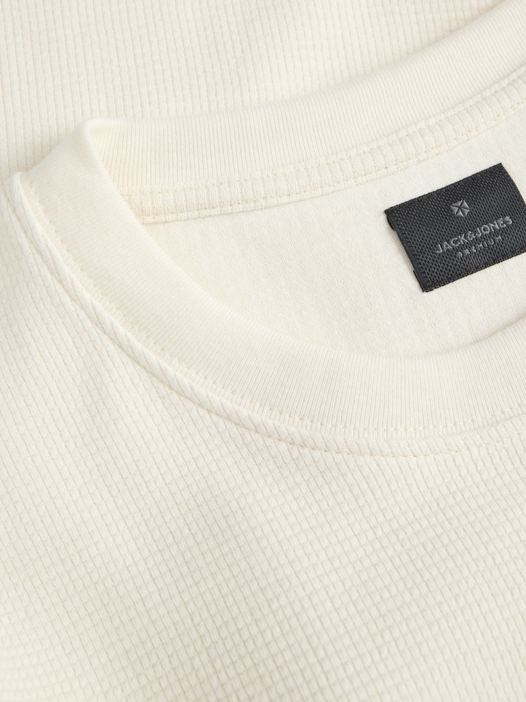 Close-up of a white tee with a black label featuring 'Jack and Jones' branding.