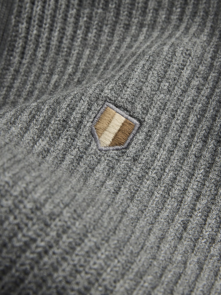 Close-up of a textured gray fabric with a small embroidered patch.