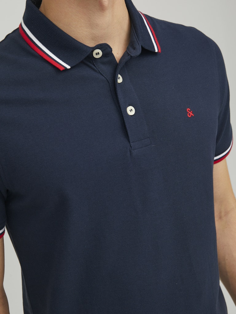 Navy blue polo shirt with white and red trim on a neutral background
