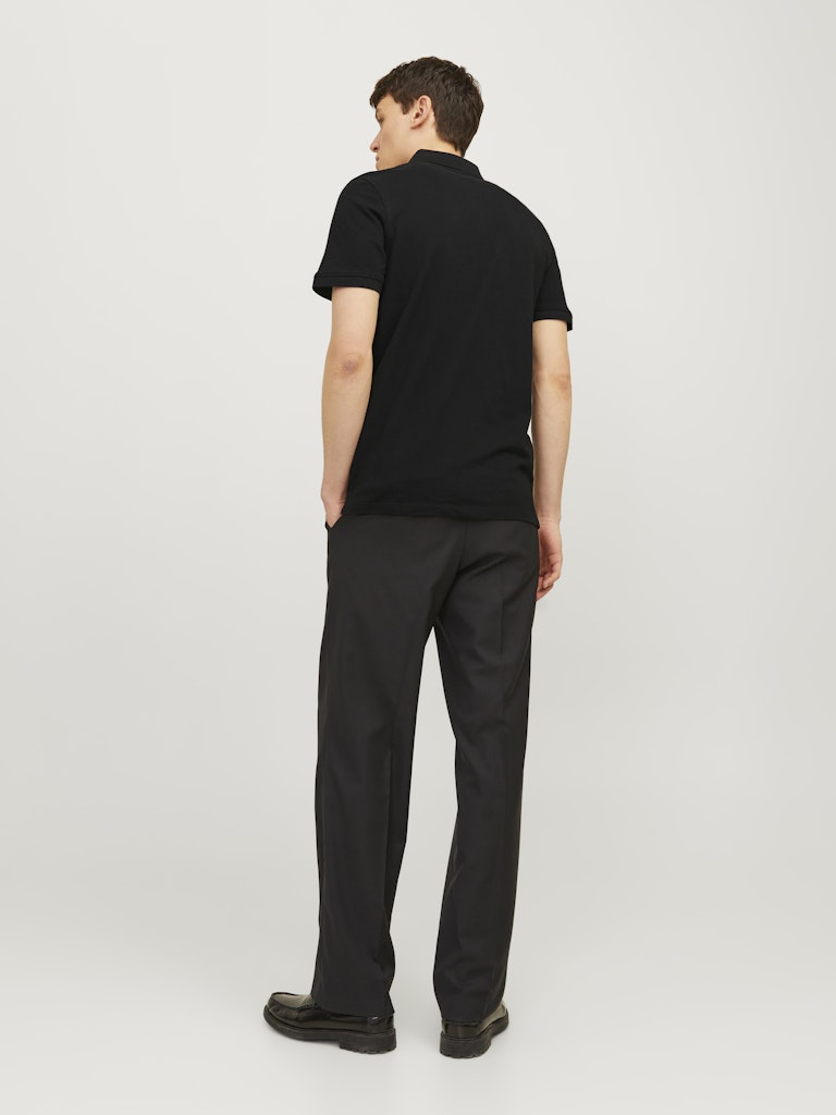 Person wearing a black polo shirt and black pants on a white background