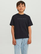 Child wearing a black t-shirt with text on a plain background