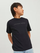 Person wearing a black t-shirt with text on a plain background