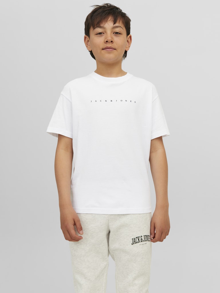Child wearing a white t-shirt and beige pants with 'Jack & Jones' branding on a plain background