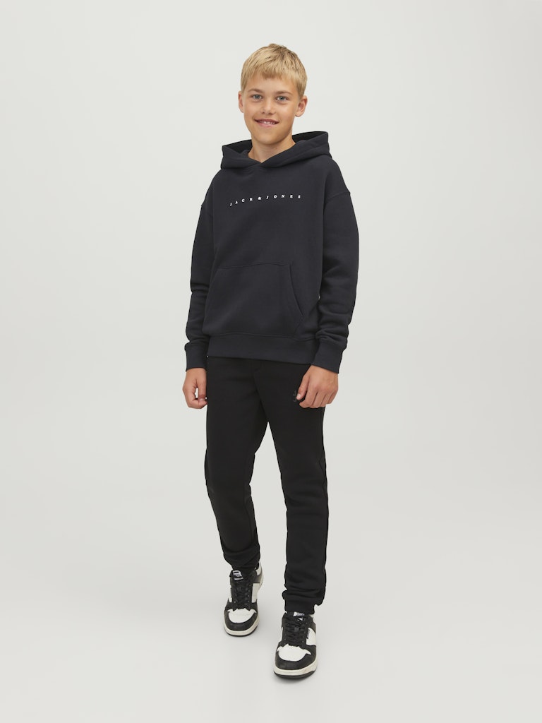 Person wearing a black hoodie and pants on a white background