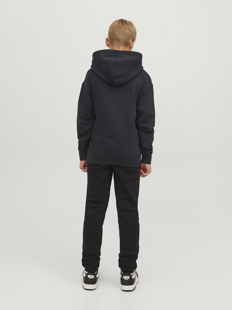 Person wearing a black hoodie and pants on a white background