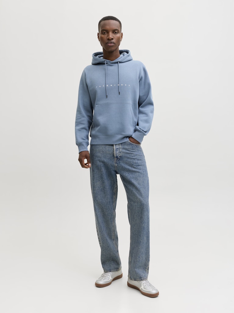 Person wearing a light blue hoodie and jeans on a white background