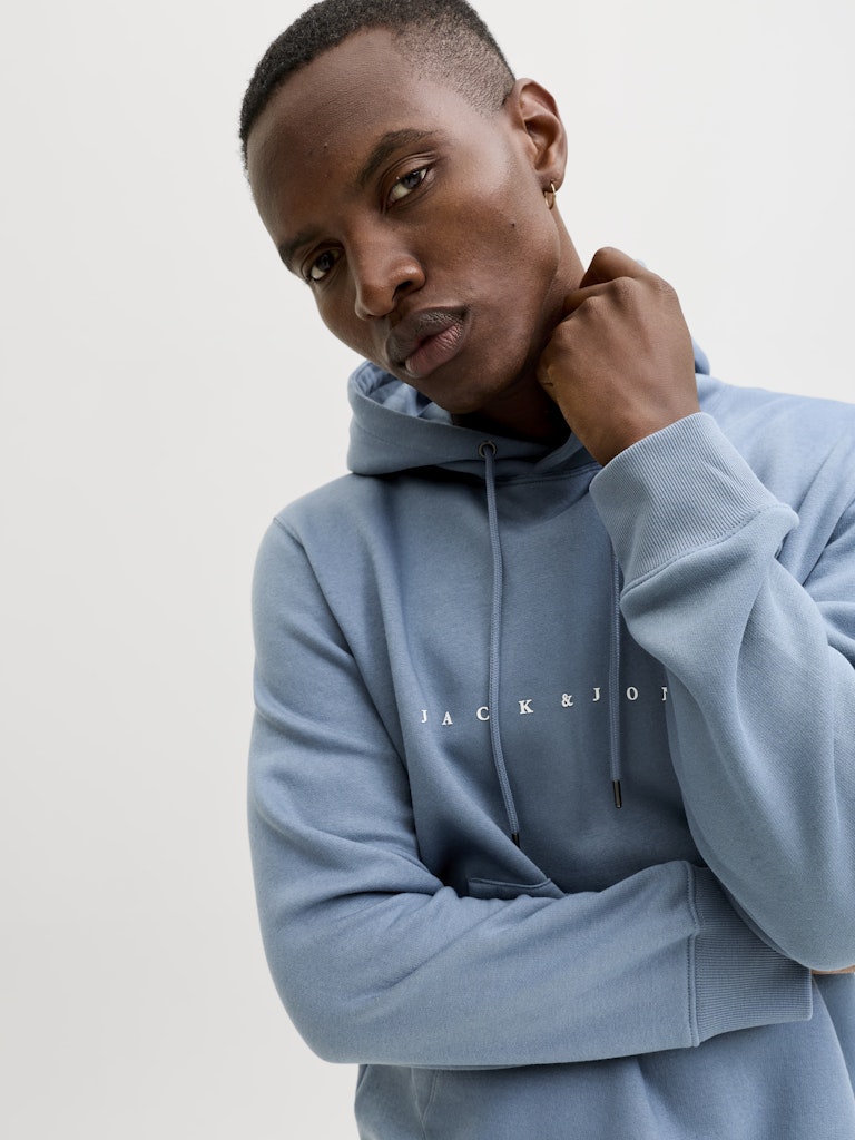 Person wearing a light blue hoodie with 'JACK & JONES' branding on a plain background