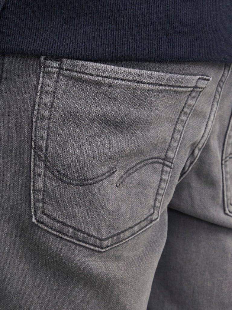 Close-up of gray jeans with a pocket detail, worn by a person.