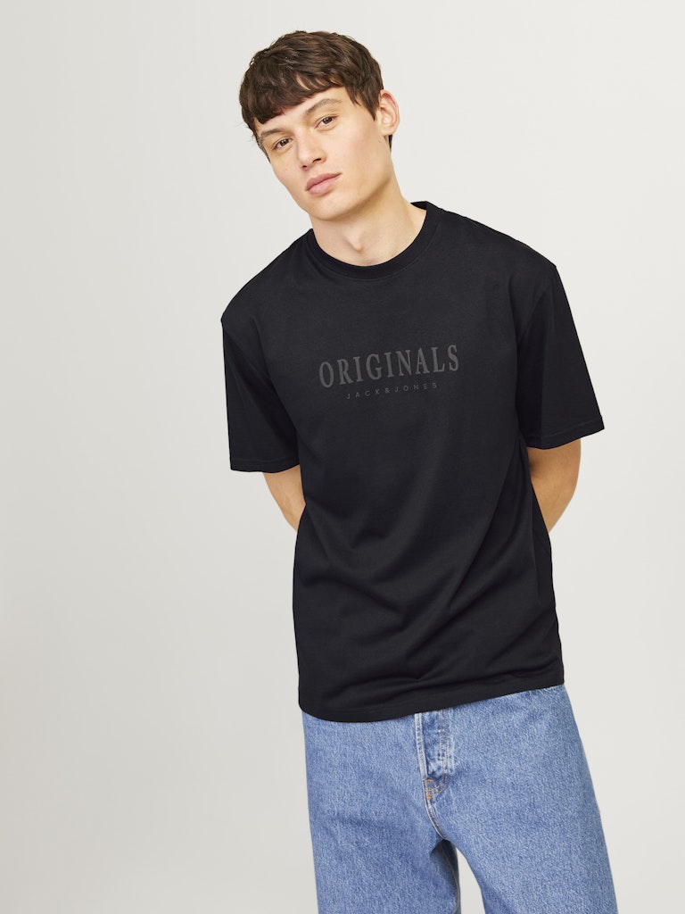 Person wearing a black t-shirt with 'ORIGINALS' text on a plain background