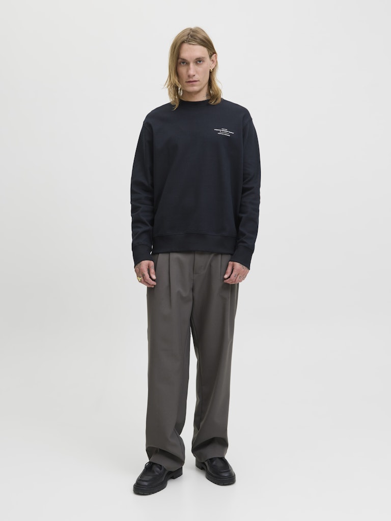 Person wearing a black sweatshirt and gray pants on a white background