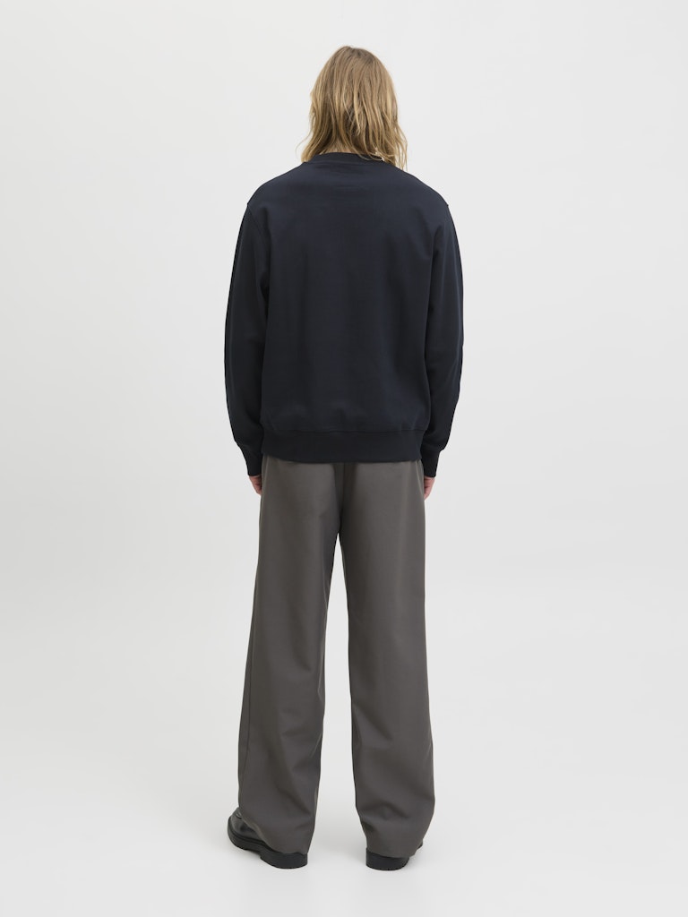 Person wearing a black sweater and gray pants on a white background