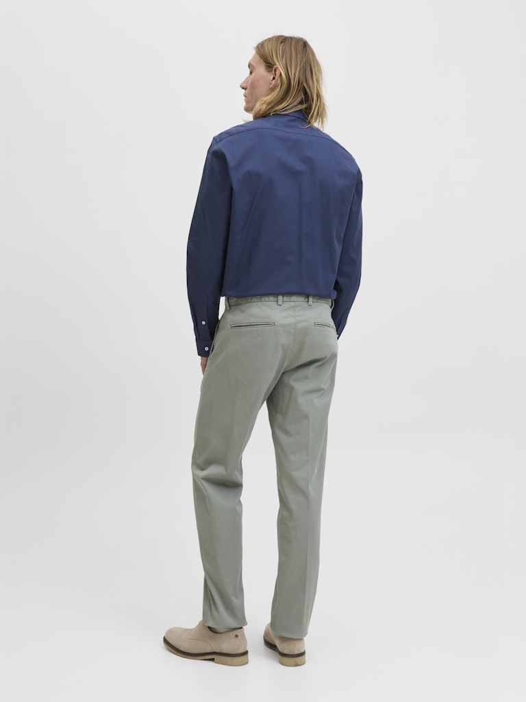 Person wearing a blue shirt and gray pants on a white background