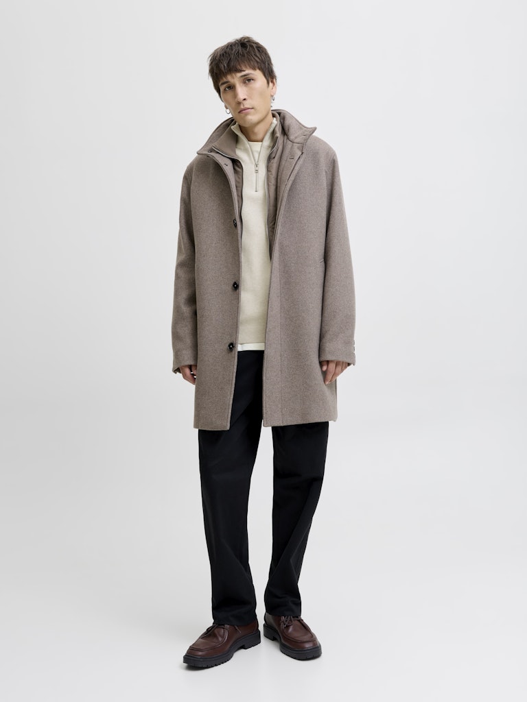 Person wearing a long brown coat on a white background