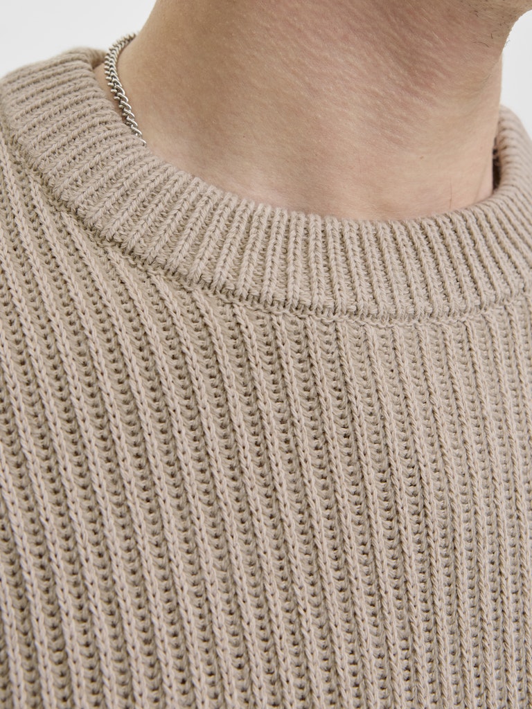 Close-up of a beige knitted sweater with a plain background