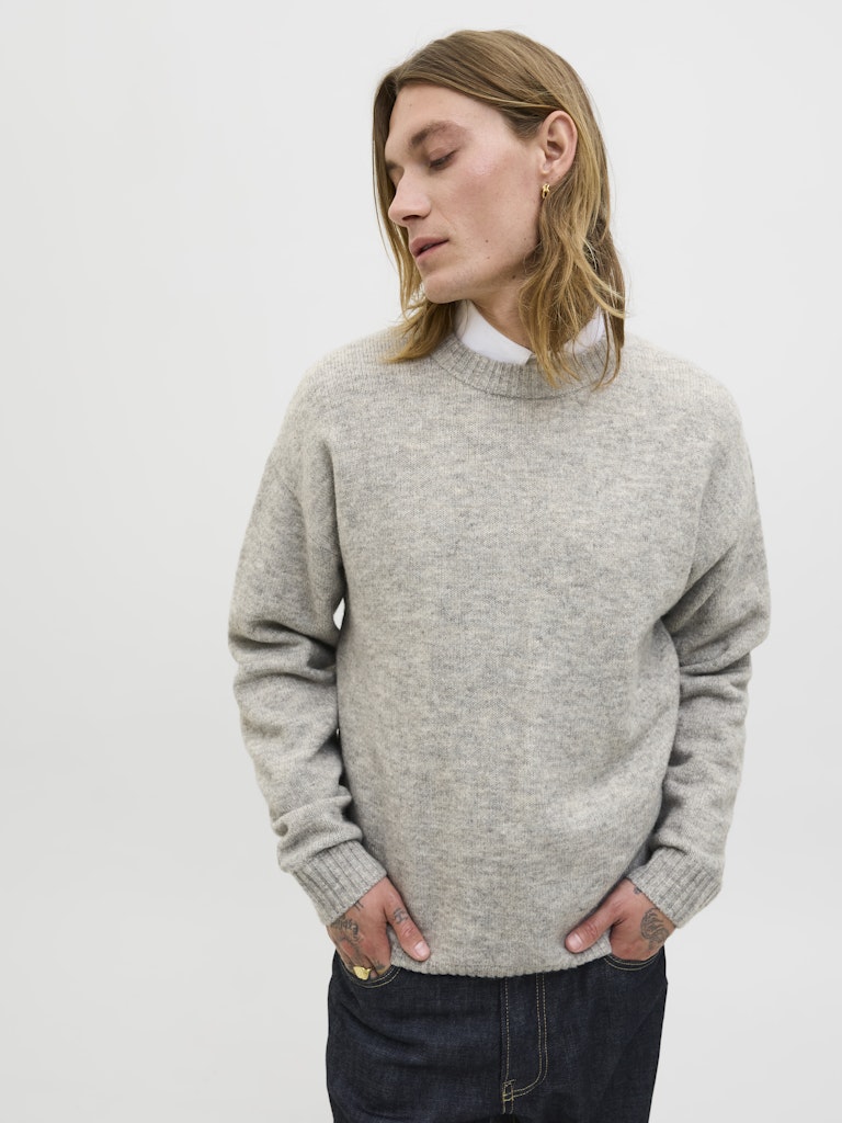 Person wearing a gray sweater on a white background
