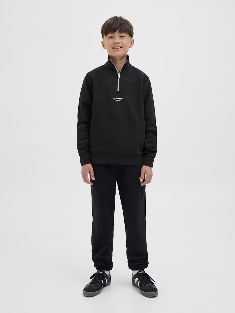 Person wearing a black tracksuit with a logo on a white background