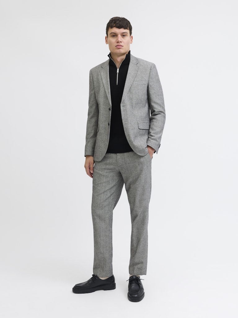 Man wearing a gray suit with a black shirt on a white background