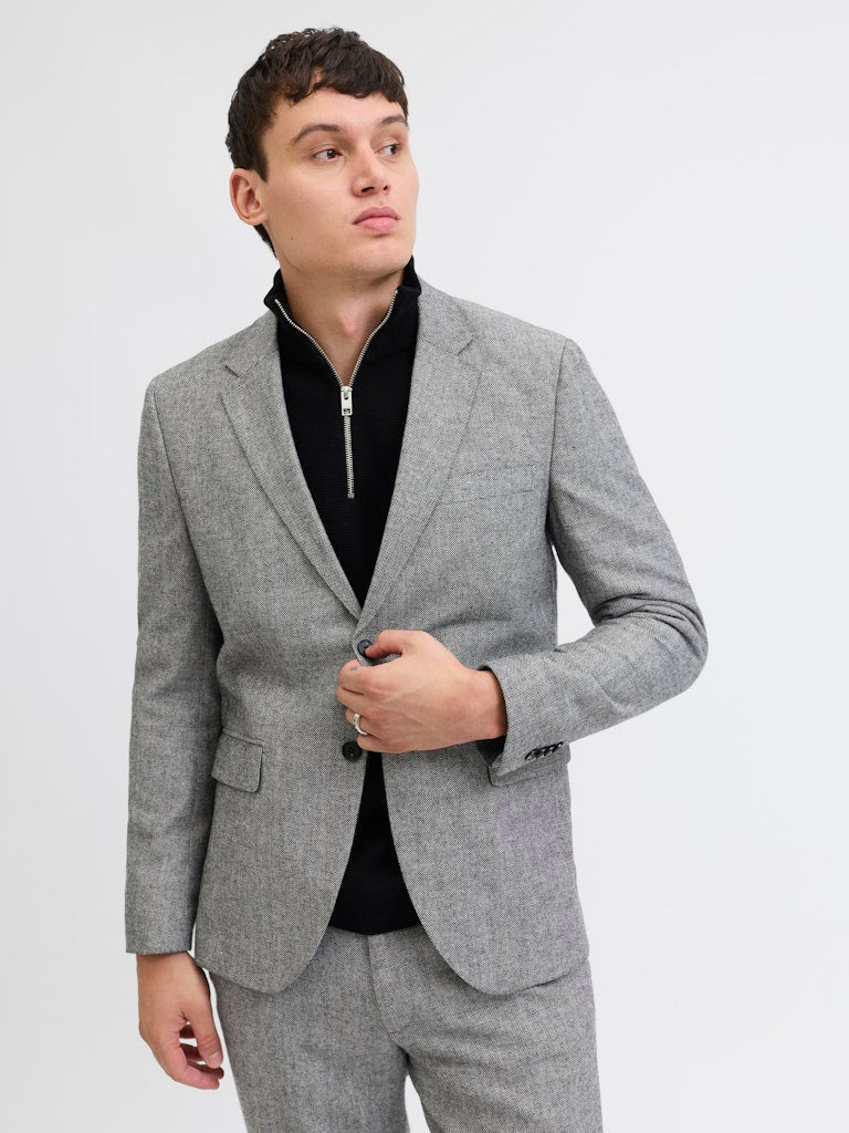 Man wearing a gray suit jacket and pants on a light gray background