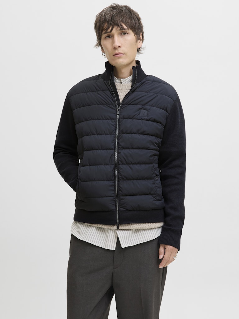 Person wearing a navy puffer jacket on a light gray background