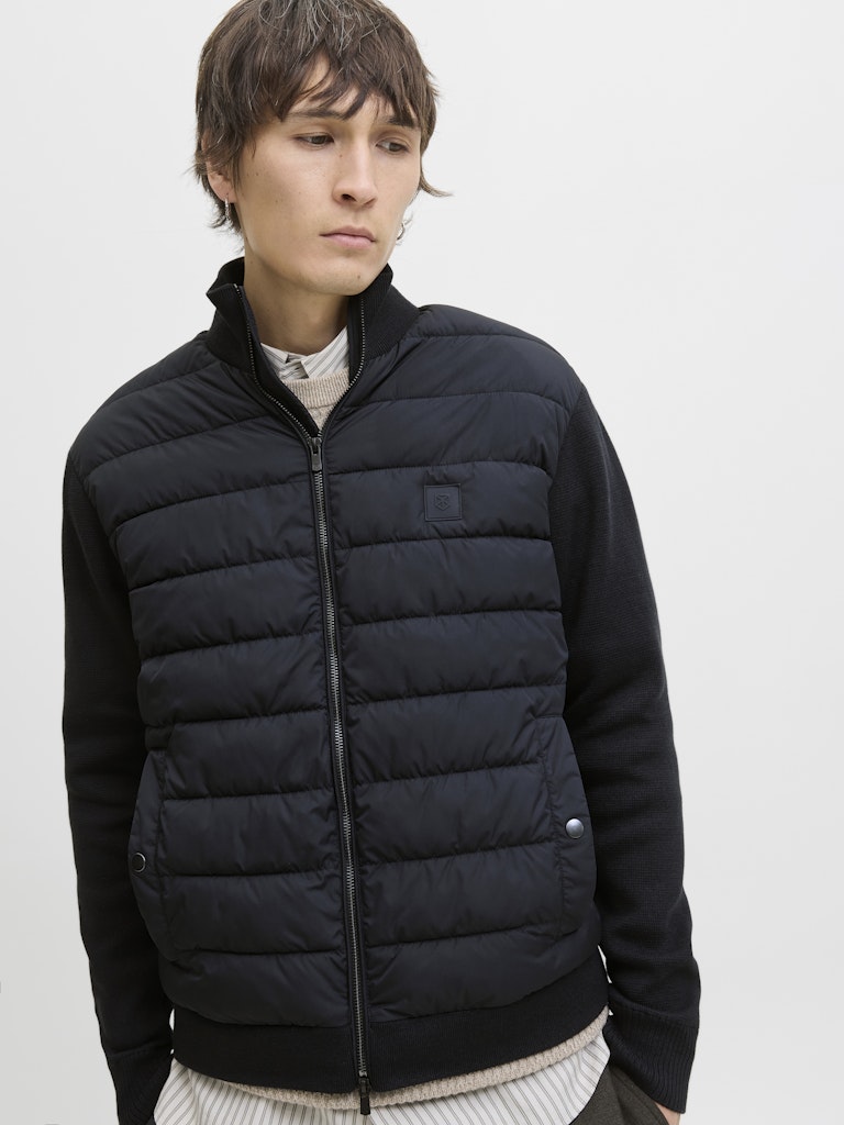 Person wearing a navy puffer jacket on a light gray background